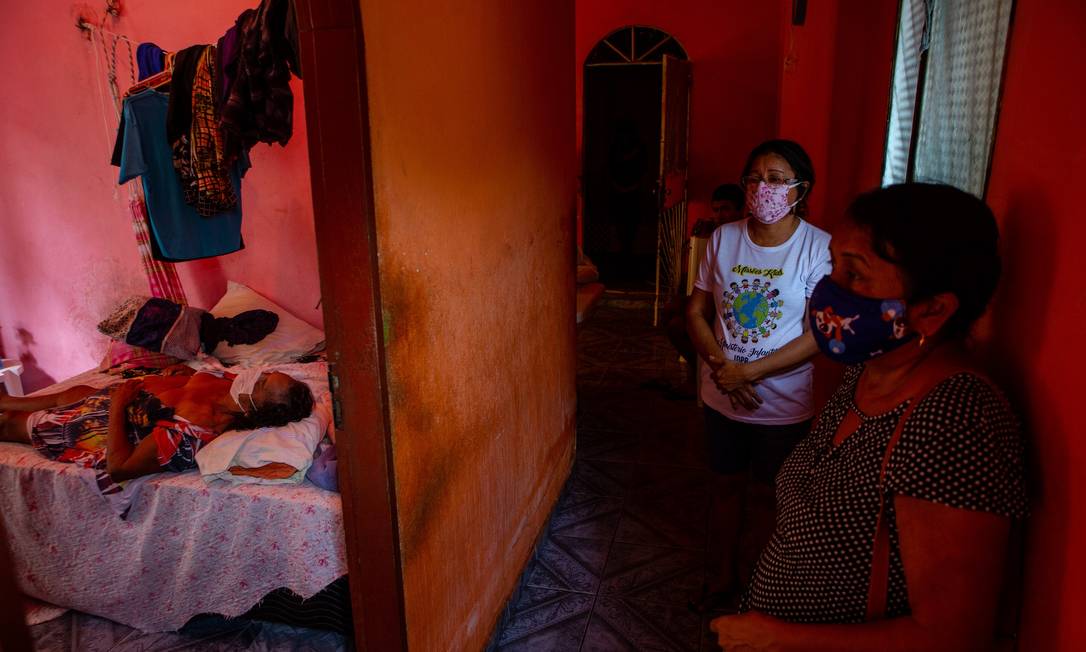 O corpo de Francisca Ribeiro Bentes, 75 anos, é visto sobre a cama enquanto a filha, Elaine Bentes Carneiro, de 55 anos, aguarda a remoção, em Manaus Foto: Yan Boechat / Agência O Globo - 30/04/2020