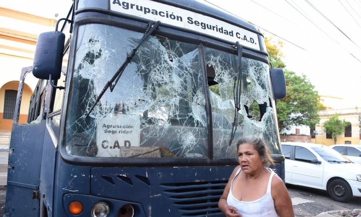 Mulher passa por ônibus cujas janelas foram quebradas durante um protesto contra má gestão do presidente Benítez contra a pandemia da Covid-19 Foto: NORBERTO DUARTE / AFP