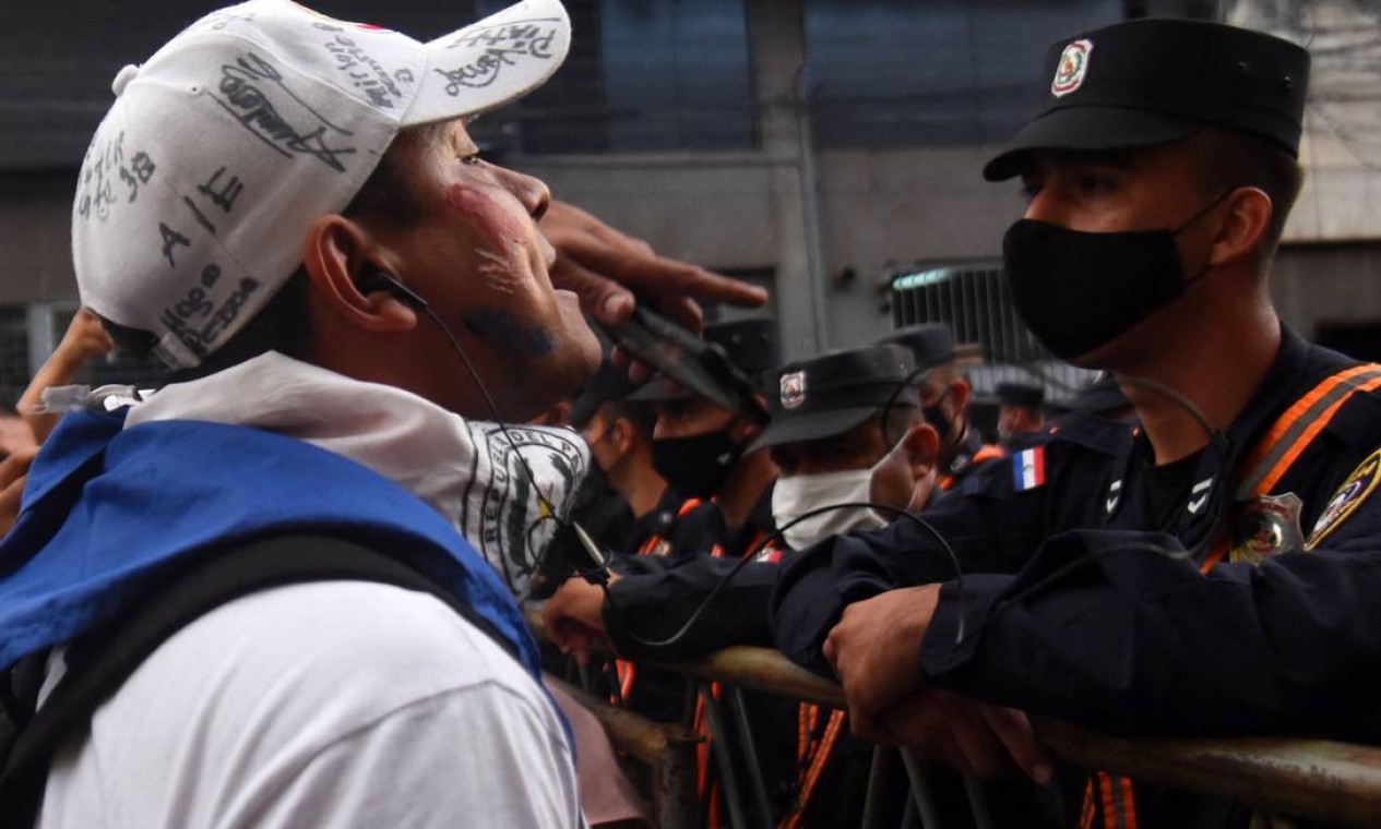 Manifestante enfrenta policial durante protesto contra má gestão na pandemia do presidente paraguaio, Mario Abdo Benítez Foto: NORBERTO DUARTE / AFP