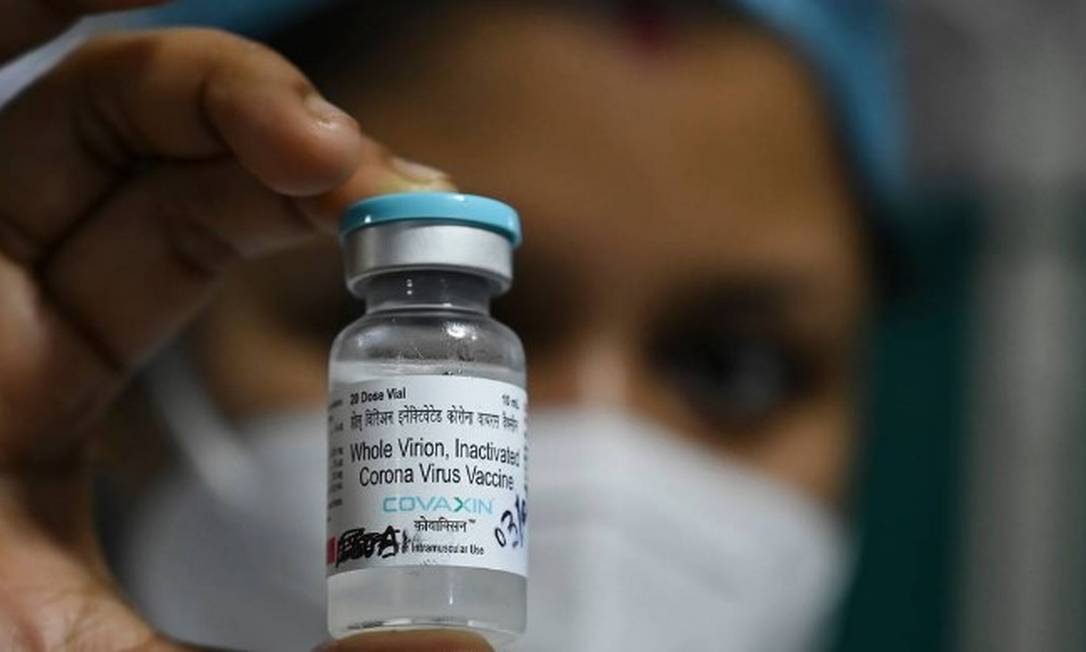 Profissional de saúde segura frasco da vacina indiana Covaxin, na Índia Foto: DIBYANGSHU SARKAR/AFP