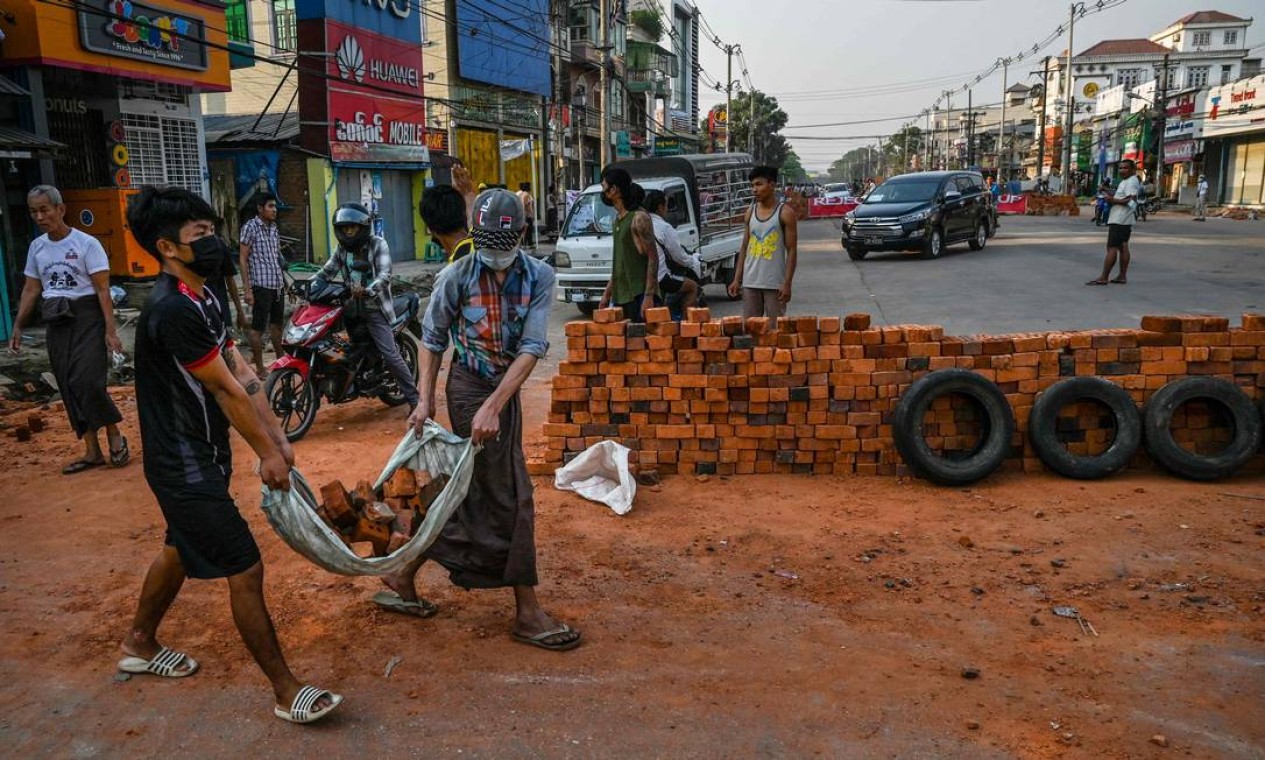 Manifestantes carregam tijolos para construir barricada deter as forças de segurança durante as manifestações contra o golpe militar em Yangon Foto: STR / AFP