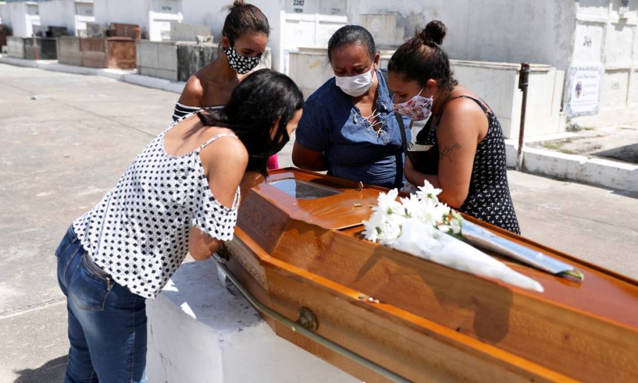 Parentes de Luiz Alves, 63, vítima da COVID-19, reúnem-se ao redor do caixão no cemitério de Inhaúma, no Rio de Janeiro Foto: Pilar Olivares / Reuters - 10/03/2021