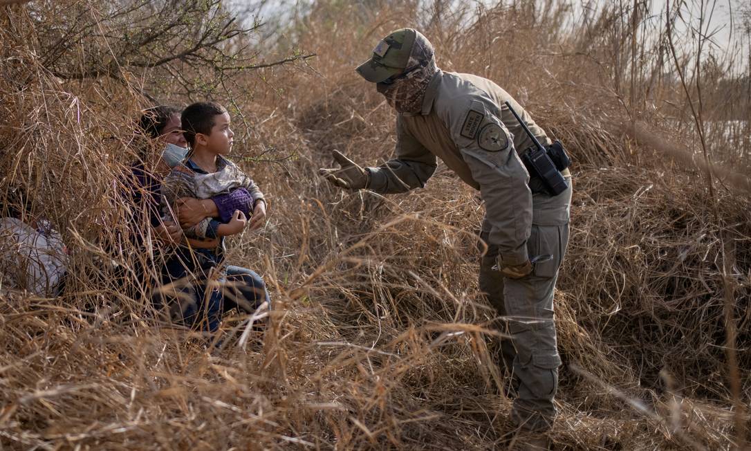 Um policial estadual do Texas conversa com Edith e seu filho Harbin Ordonez, de 4 anos, perto do Rio Grande Foto: ADREES LATIF / REUTERS