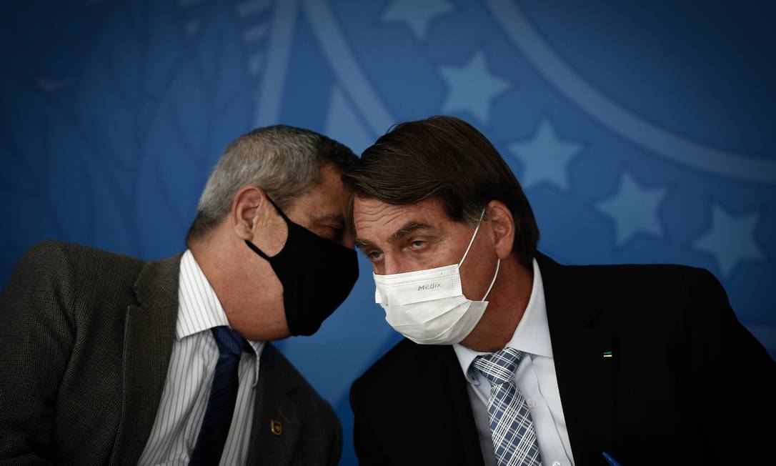 The then Prime Minister of the Civil House, Braga Netto, speaks in Bolsonaro's ear, during a ceremony in which the president signed laws that increase the federal government's ability to purchase vaccines.  Despite the use of a mask, which became an unusual scene for the president, the distance between members of the government was not maintained Photo: Pablo Jacob / Agência O Globo - 03/10/2021