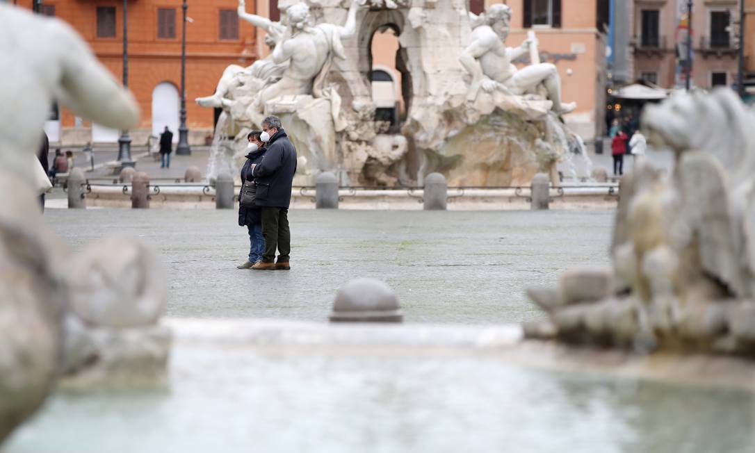 De máscara, casal observa a Piazza Navona, em Roma, horas antes do governo anunciar novas restrições Foto: YARA NARDI / REUTERS