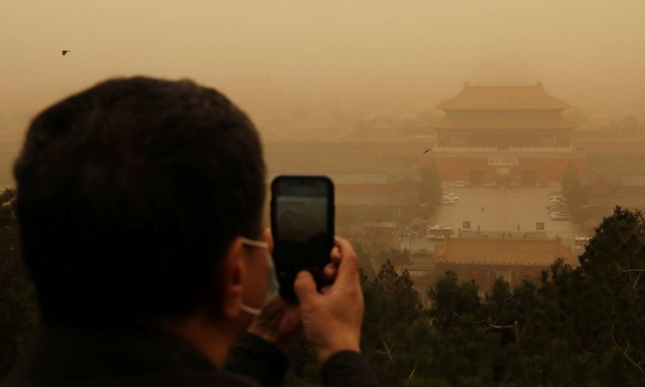 Vistiante fotografa a Cidade Proibida no Parque Jingshan, enquanto Pequim é atingida por uma tempestade de areia Foto: TINGSHU WANG / REUTERS