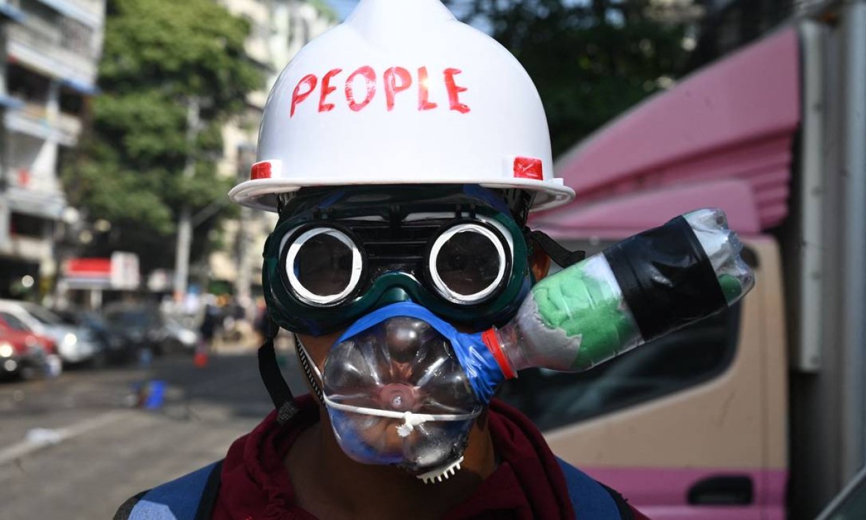 Com capacete de construção civil, óculos e garrafas PET, manifestante improvisa EPI Foto: STR / AFP