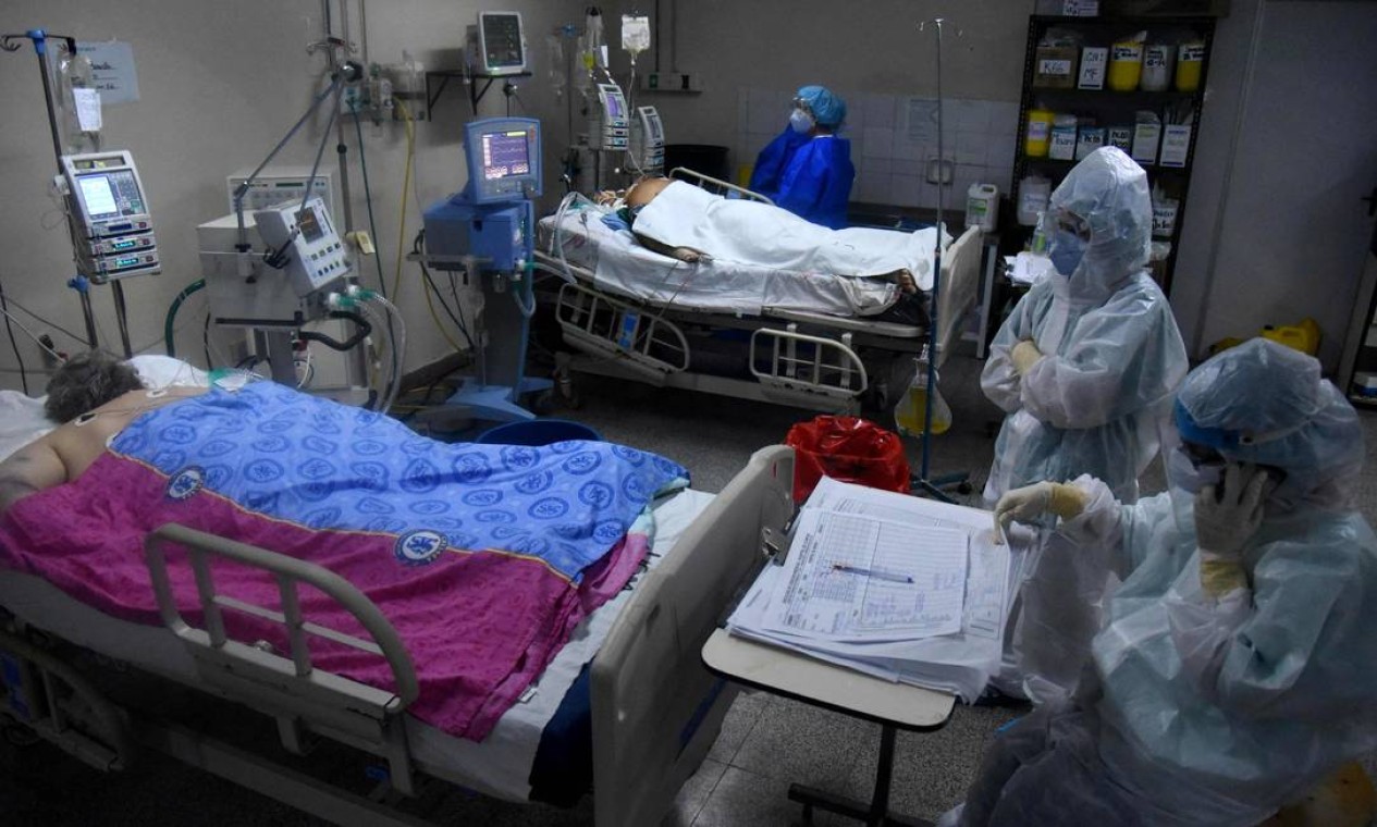 Profissionais de saúde atendem pacientes com COVID-19 na unidade de terapia intensiva do Hospital das Clínicas de San Lorenzo, Paraguai. O governo do Paraguai reforçou restrições devido ao aumento do número de casos da doença que colapsou o sistema de saúde Foto: DANIEL DUARTE / AFP