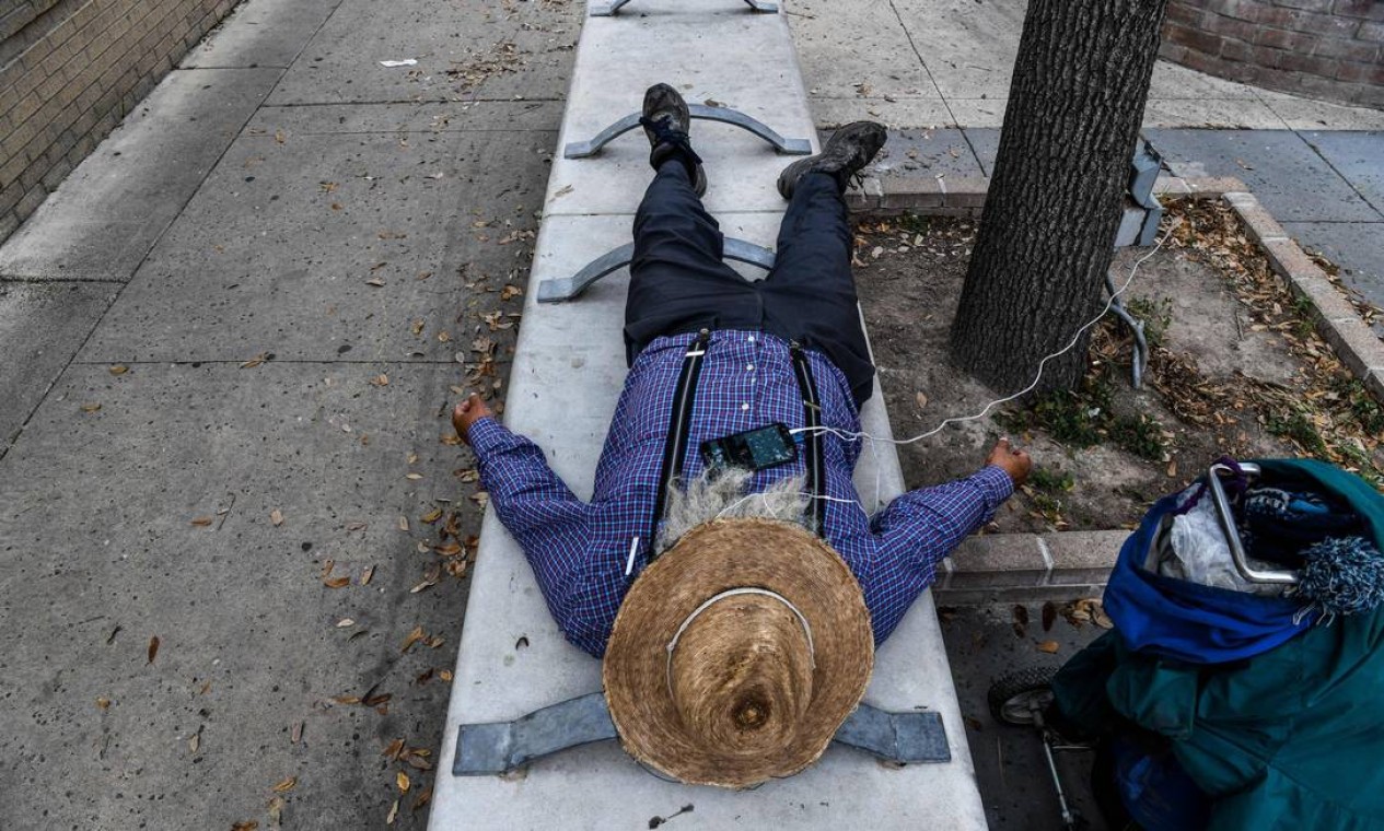 Homem dorme em um banco na calçada perto da Gateway International Bridge, entre as cidades de Brownsville, Texas, e Matamoros, México Foto: CHANDAN KHANNA / AFP
