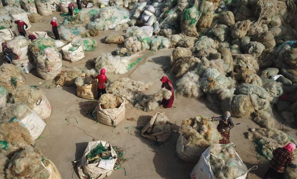 Pescadores reciclam redes em um vilarejo em Lianyungang, na província de Jiangsu, no leste da China Foto: STR / AFP