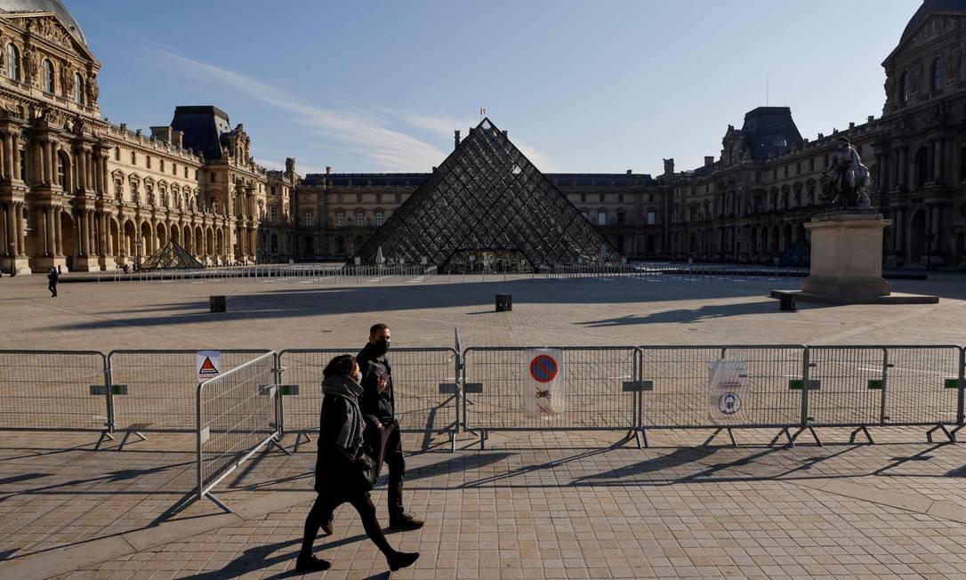 De máscara, casal caminha em frente ao Museu do Louvre, fechado durante o lockdown de novembro de 2020 Foto: LUDOVIC MARIN / AFP / 6-11-2020