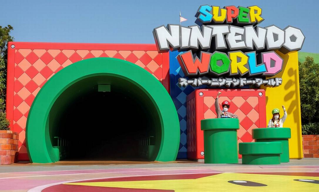 Duas visitantes com seus chapeus de Mario e Luigi posam em frente ao túnel em forma de cano que dá acesso à área temática Super Nintendo World, do Universal Studio Japan Foto: IRENE WANG / REUTERS