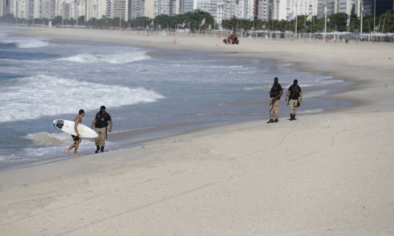 Guardas retiram surfista da praia. Novo decreto restringe, inclusive, prática esportiva individual nas praias Foto: Marcia Foletto / Agência O Globo