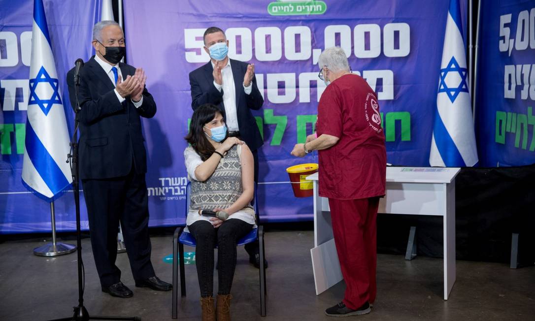 Benjamin Netanyahu (esquerda) acompanha vacinação de mulher que bateu a marca de 5 milhões de israelenses a terem recebido a primeira dose, mais da metade da população do pa Foto: POOL / REUTERS
