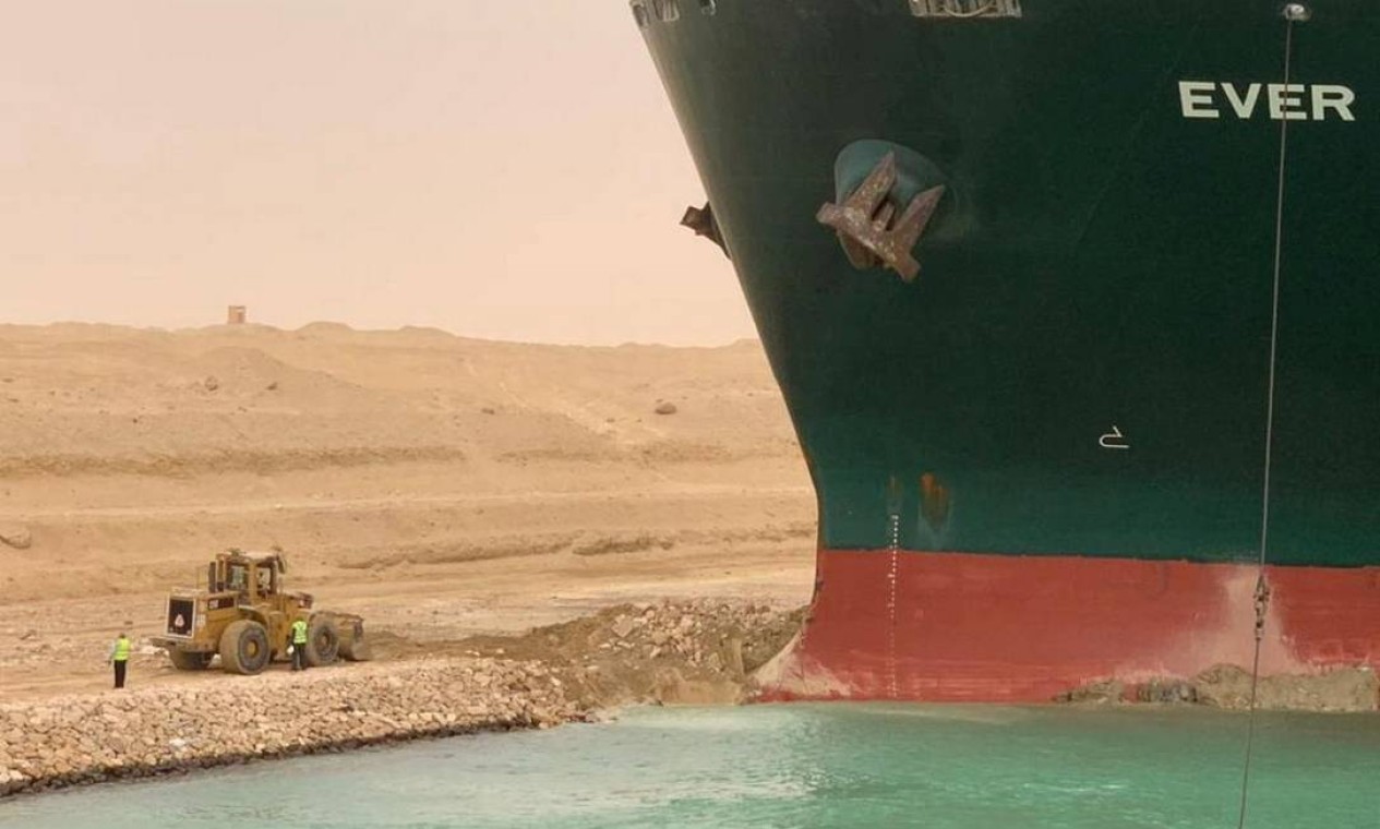 Trabalhadores são vistos próximo ao navio de contêiner que foi atingido por vento forte e encalhou no Canal de Suez, Egito Foto: Suez Canal Authority / VIA REUTERS