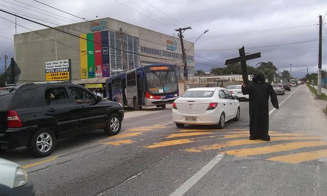 Fantasiado de morte, morador acenava com uma cruz para os motoristas na rodovia em Bertioga, no litoral de São Paulo, contra a ida das pessoas ao litoral em plena pandemia. Foto: Reprodução - G1 / Reprodução - G1