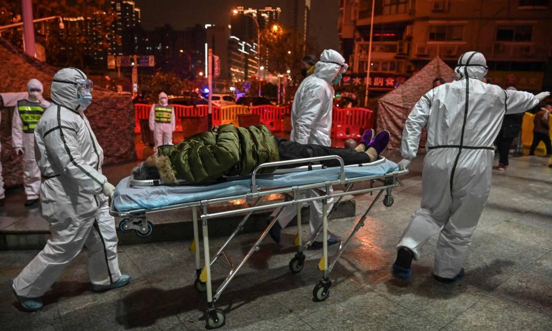 Foto de janeiro de 2020 mostra trabalhadores da linha de frente em Wuhan chegando com um paciente no hospital da Cruz Vermelha Foto: HECTOR RETAMAL / AFP/25-1-2020