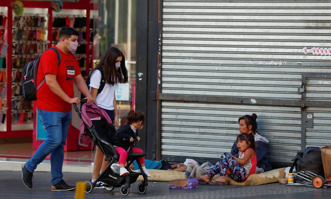 Mulher em situação de rua pede dinheiro a pessoas que passam perto, em Buenos Aires, Argentina Foto: AGUSTIN MARCARIAN / REUTERS