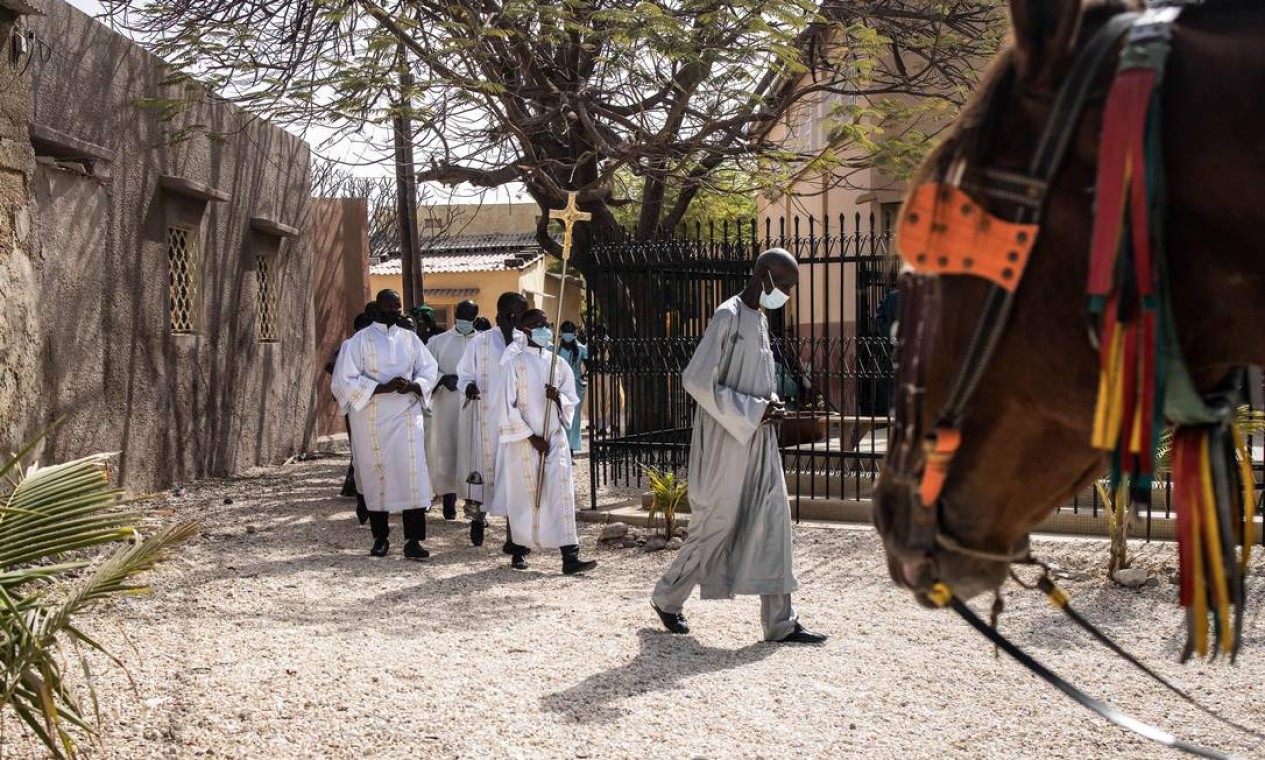 Coroinha carrega uma cruz no início da Missa de Páscoa em Fadiouth, Senegal. O país majoritariamente muçulmano tem na Ilha de Fadiouth uma concentração de cerca de noventa por cento de cristãos Foto: JOHN WESSELS / AFP