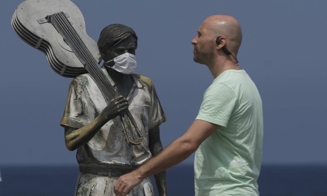 Em 25 de março estátua de Tom Jobim na praia do Arpoador tinha máscara de proteção enquanto pessoas passeavam no local sem o acessório Foto: Márcia Foletto / Agência O Globo