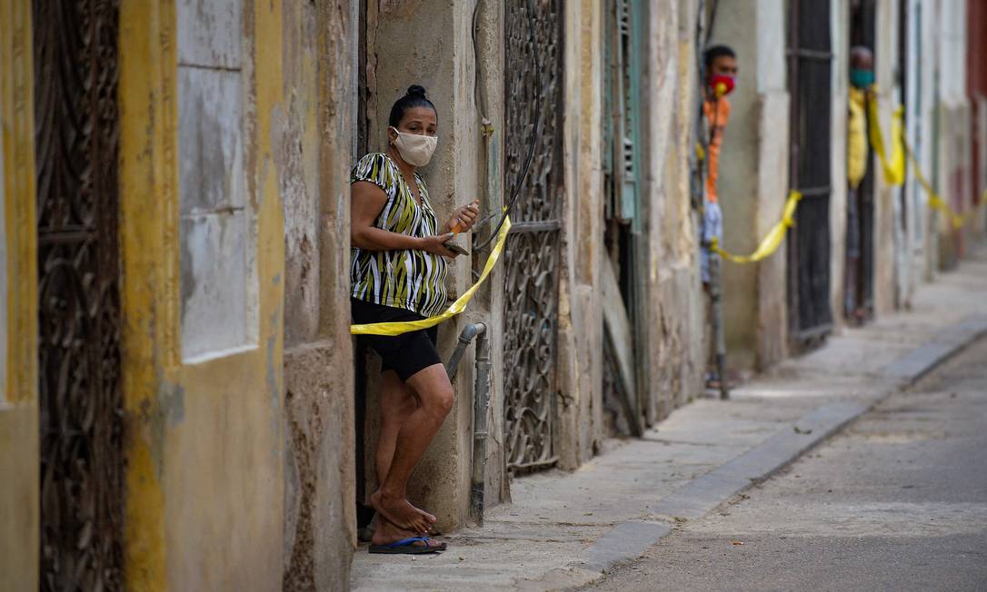 Cubanos nas portas de suas casas em área restrita após avanço de casos de Covid-19 em Havana Foto: YAMIL LAGE / AFP