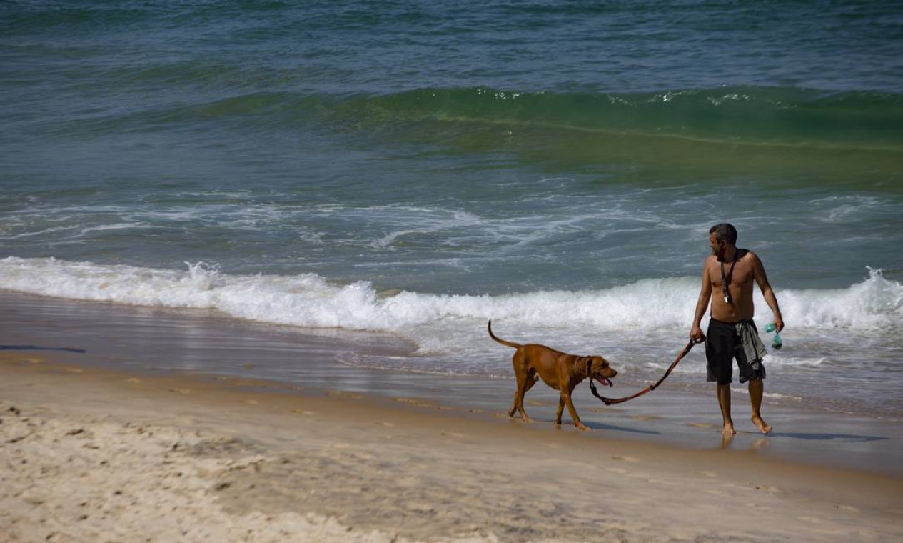 Homem passeia com cachorro à beira-mar, na praia do Arpoador, em Ipanema, Zona Sul do Rio Foto: Maria Isabel Oliveira / Agência O Globo