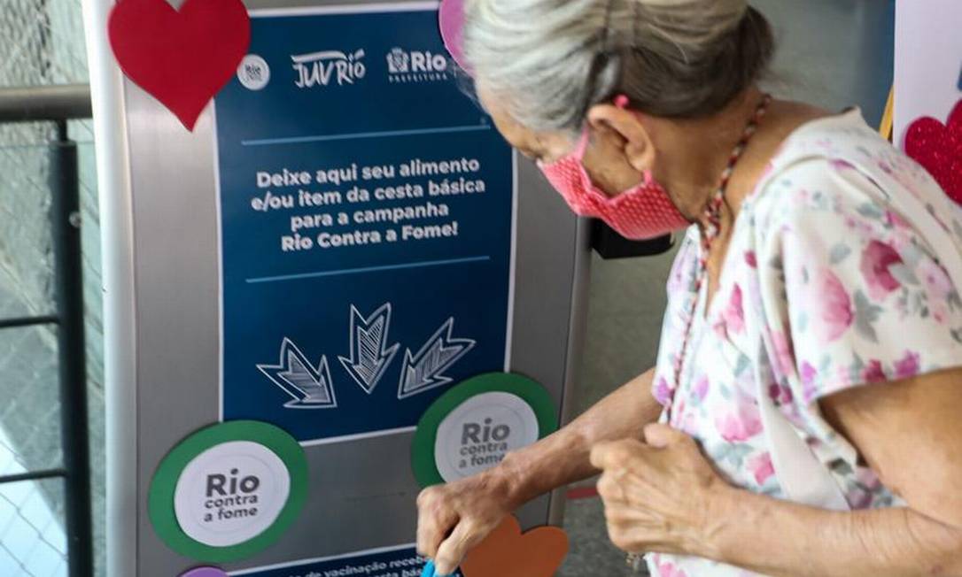 Ao se vacinar contra a covid-19, idosa leva alimento para ajudar a campanha "Rio Contra a Fome". Em uma semana, iniciativa arrecadou 7 toneladas em doações. Foto: Bernardo Cordeiro / Divulgação