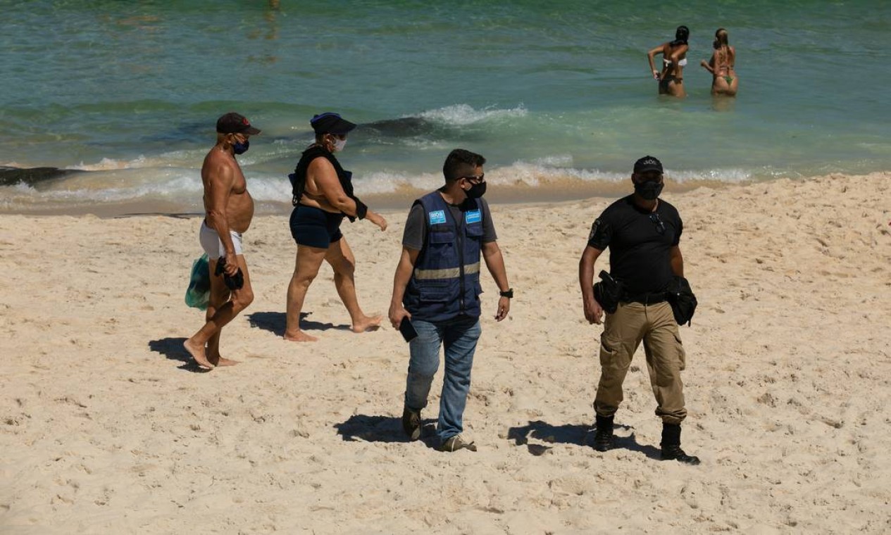 Guardas Municipais no Arpoador tiveram trabalho para tentar retirar da areia banhistas que insistiam em permanecer na praia, o que segue proibido Foto: Brenno Carvalho / Agência O Globo