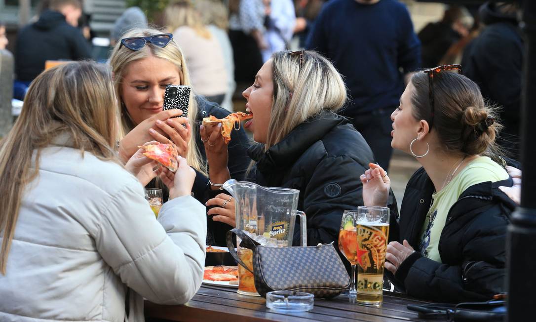 Grupo de amigas come pizza em bar de Leeds, no Nordeste do Reino Unido Foto: LINDSEY PARNABY / AFP