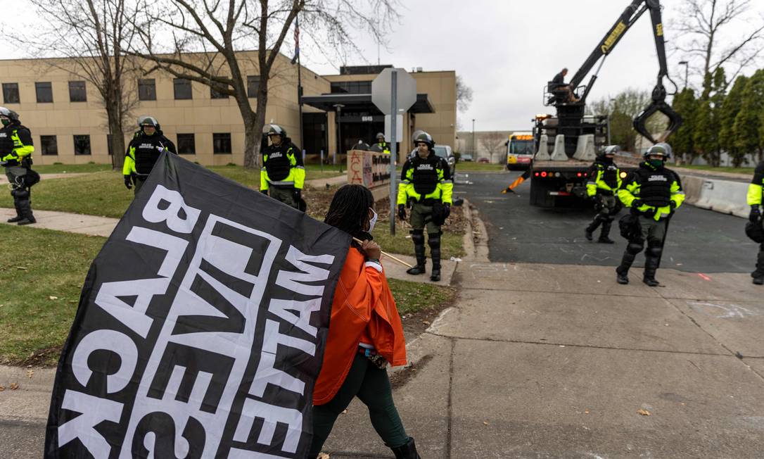 Manifestante protesta com uma bandeira do movimento "Black Lives Matter", em frente a delegacia de Brooklyn Center, Minneapolis, onde policial matou um homem negro Foto: KEREM YUCEL / AFP