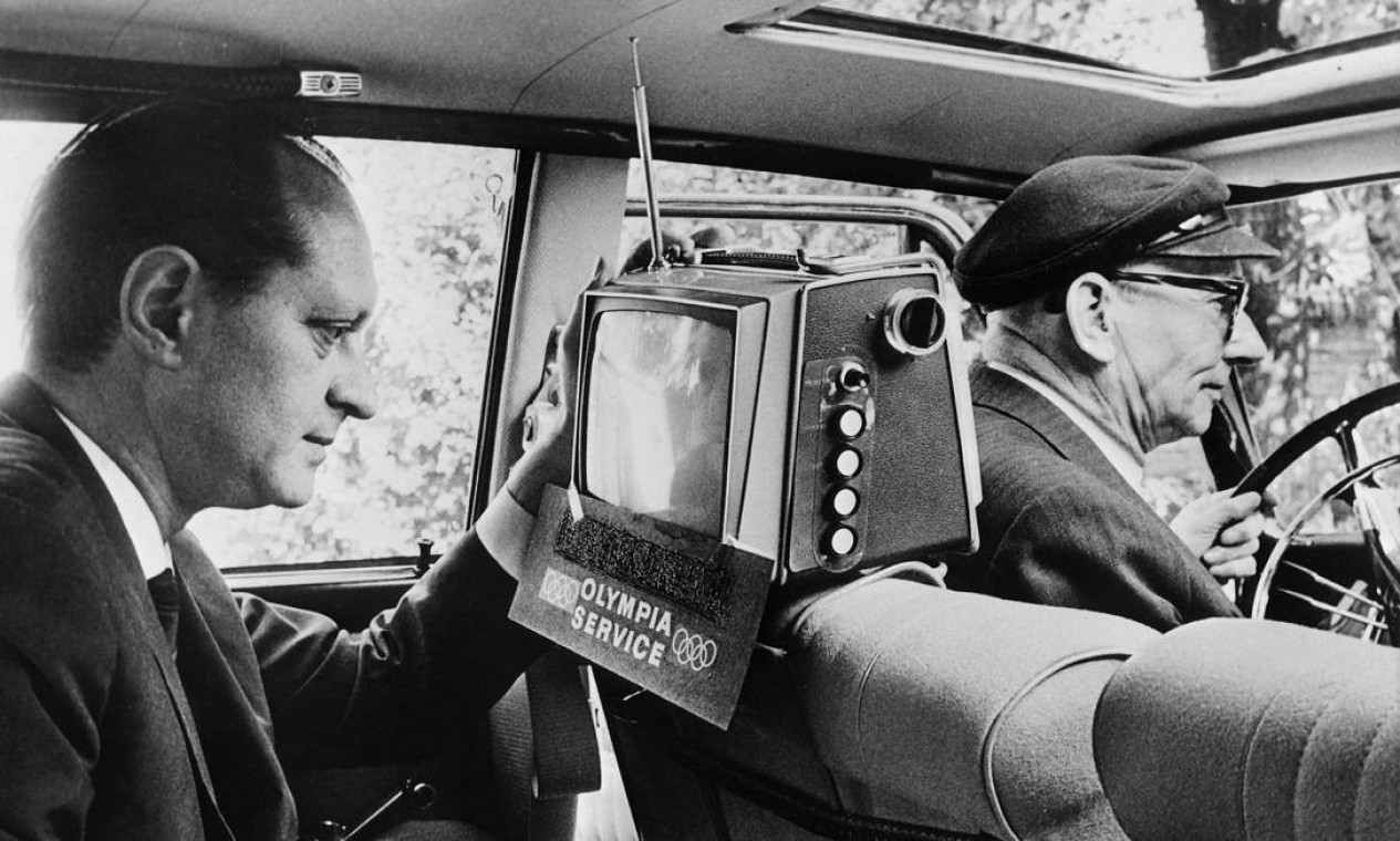 Em Hamburgo, passageiro em um táxi assiste aos jogos em uma TV portátil. Os primeiros Jogos já realizados na Ásia também foram uma chance de alardear a reconstrução da Tóquio do pós-guerra e o surgimento do país como um gigante de alta tecnologia Foto: Arquivo / AFP
