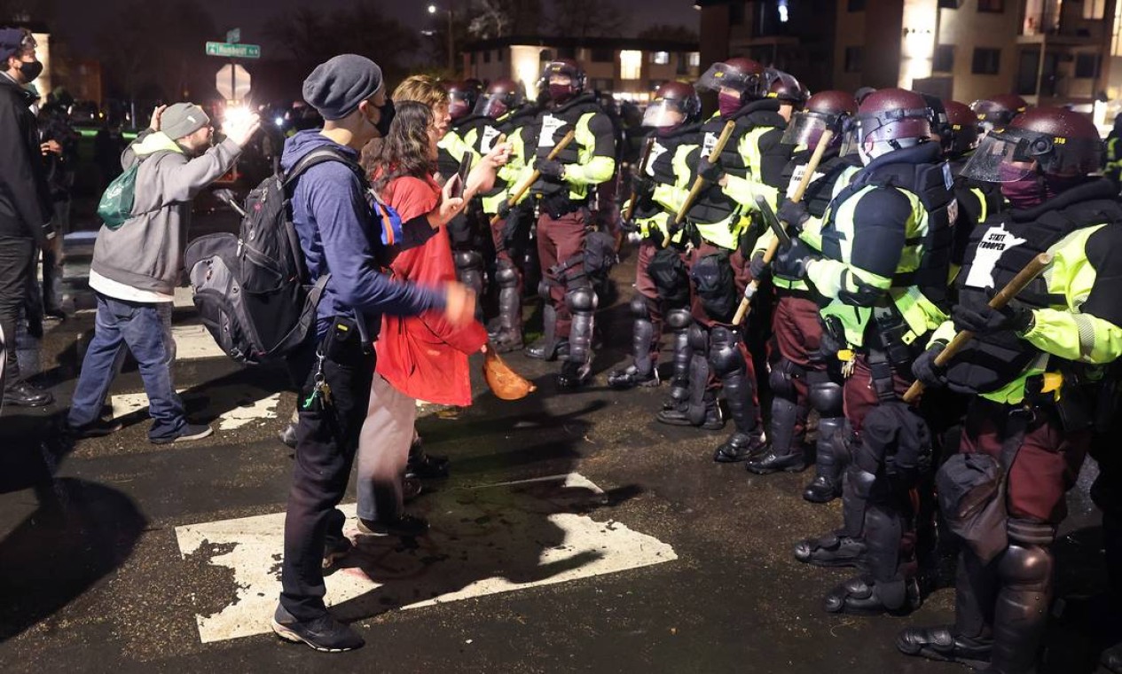 Manifestantes confrontam policiais fora da delegacia do Brooklyn Center. Kim Potter, a policial que atirou fatalmente em Daunte Wright no domingo, pediu demissão do Departamento de Polícia Foto: SCOTT OLSON / AFP
