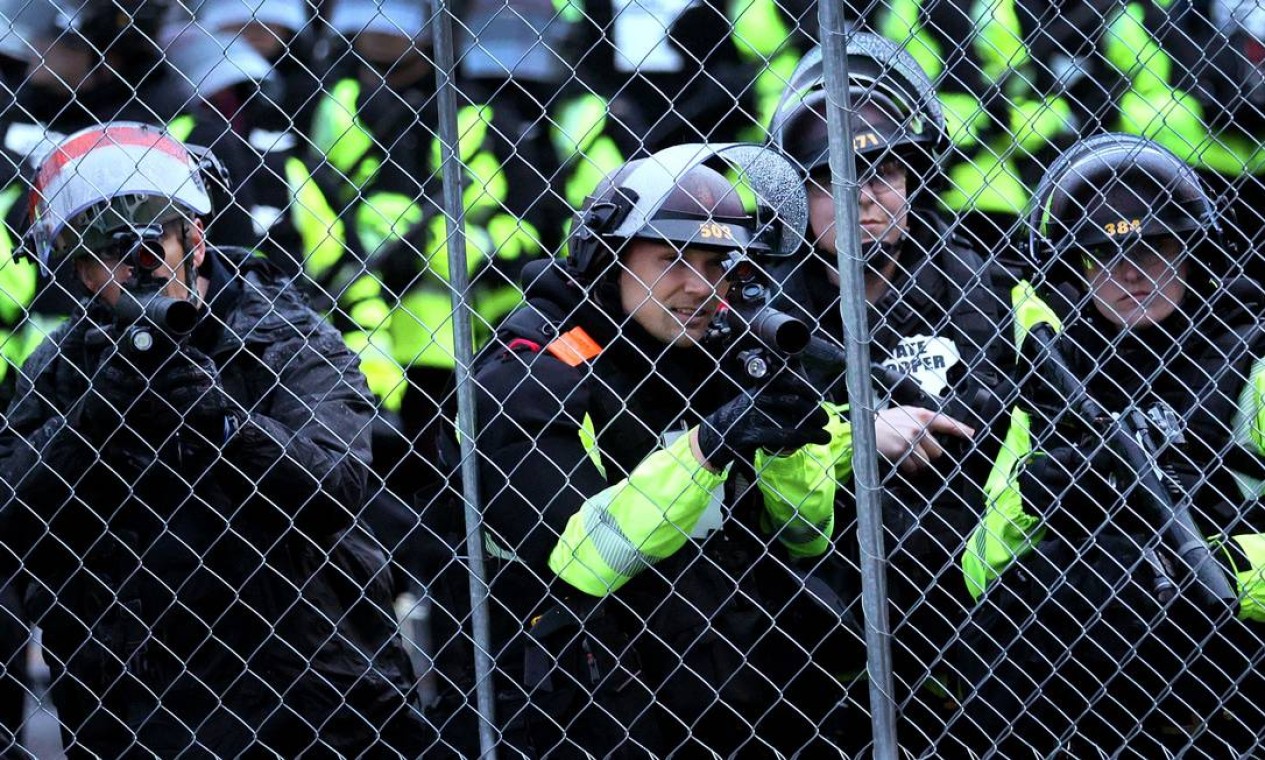 Policiais montam guarda enquanto enfrentam os manifestantes do lado de fora da delegacia do Centro de Brooklyn. A agente responsável pelo disparo sacou acidentalmentge a arma de fogo ao invés do taser, uma pistola elétrica de imobilização Foto: SCOTT OLSON / AFP