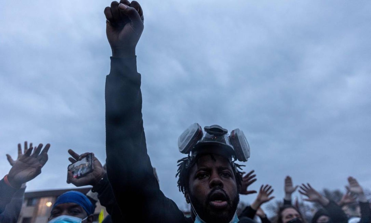 Manifestantes erguem os punhos no início do toque de recolher para protestar contra a morte de Daunte Wright Foto: KEREM YUCEL / AFP
