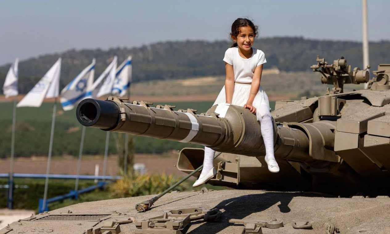 Garota se senta no canhão de tanque no memorial do Corpo de Blindados de Israel, em Latrun, entre Jerusalém e Tel Aviv, após uma cerimônia em comemoração ao Yom HaZikaron (Dia da Lembrança de Israel para os soldados mortos) Foto: JACK GUEZ / AFP