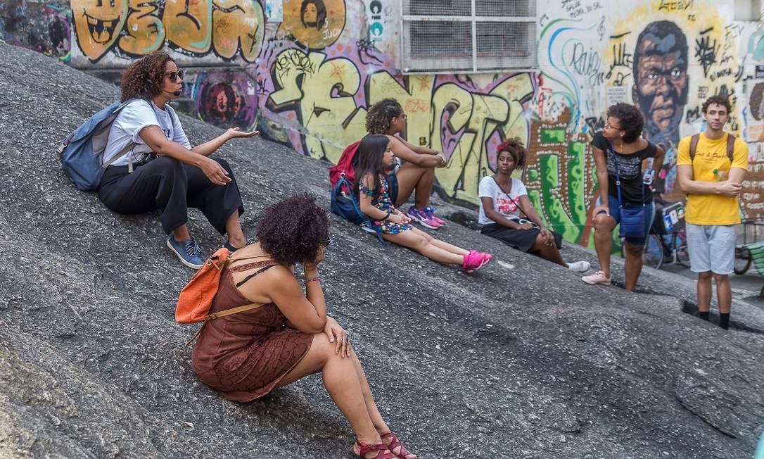 Gabriela Palma (de branco, sentada à esquerda), sócia da agência Sou + Carioca, guia um grupo pela Gamboa, durante o tour da Pequena África, na Zona Portuária do Rio, antes da pandemia Foto: Leo Henck / Acervo pessoal