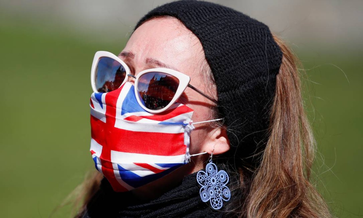 Mulher usando uma máscara facial Union Jack está do lado de fora do Castelo de Windsor durante o funeral do príncipe Philip da Grã-Bretanha, em Windsor Foto: PETER CZIBORRA / REUTERS