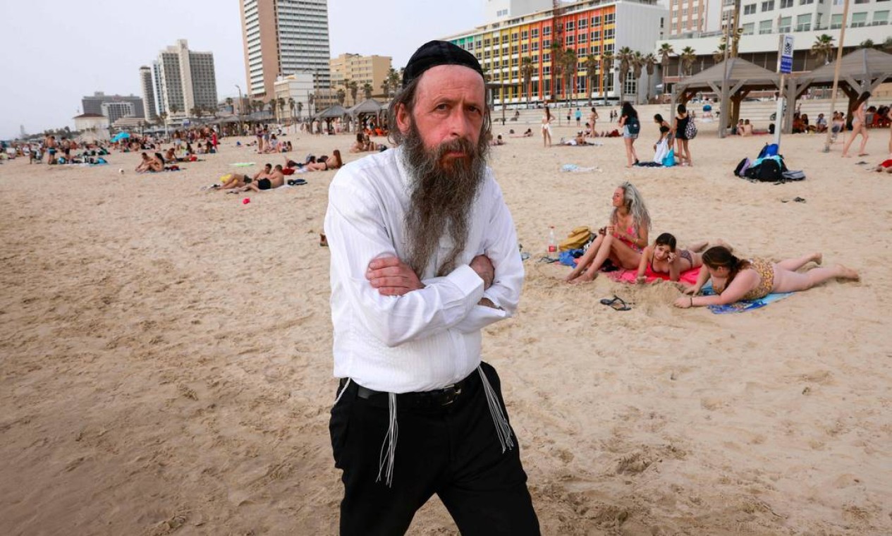 Judeu ultraortodoxo caminha em uma praia na cidade costeira israelense de Tel Aviv, depois que as autoridades anunciaram que as máscaras faciais para prevenção COVID-19 não eram mais necessárias em locais abertos. Com mais da metade da população totalmente vacinada em uma das campanhas mais rápidas do mundo, o número de casos de coronavírus em Israel caiu de cerca de 10.000 novas infecções por dia em meados de janeiro para cerca de 200 casos Foto: MENAHEM KAHANA / AFP