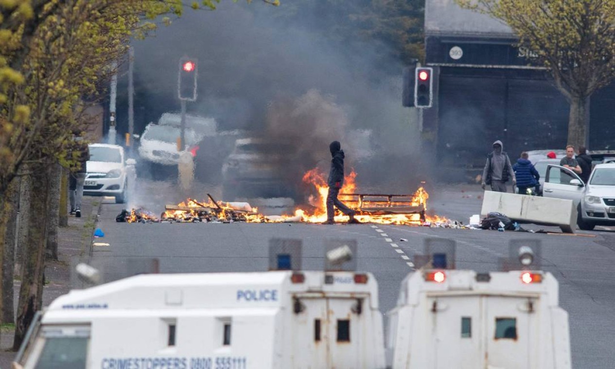 Manifestante passa por barricada em chamas em Lanark Way, no oeste de Belfast. Após uma pausa para o funeral do príncipe Philip, a Irlanda do Norte voltou a viver protestos nacionalistas contra o Brexit Foto: PAUL FAITH / AFP
