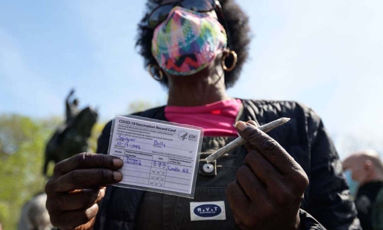 Mulher mostra seu cartão de vacinação e um baseado oferecido gratuitamente em Nova York Foto: ANGELA WEISS / AFP