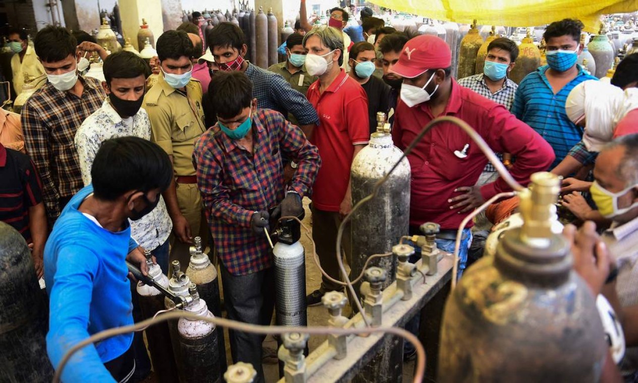 Pessoas reabastecem cilindros médicos de oxigênio para pacientes com Covid-19 em uma estação em Allahabad Foto: SANJAY KANOJIA / AFP