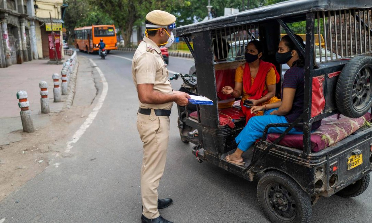 Policial verifica passageiros em um bloqueio rodoviário em Nova Delhi, enquanto a Índia mantém sua capital fechada por uma semana Foto: JEWEL SAMAD / AFP