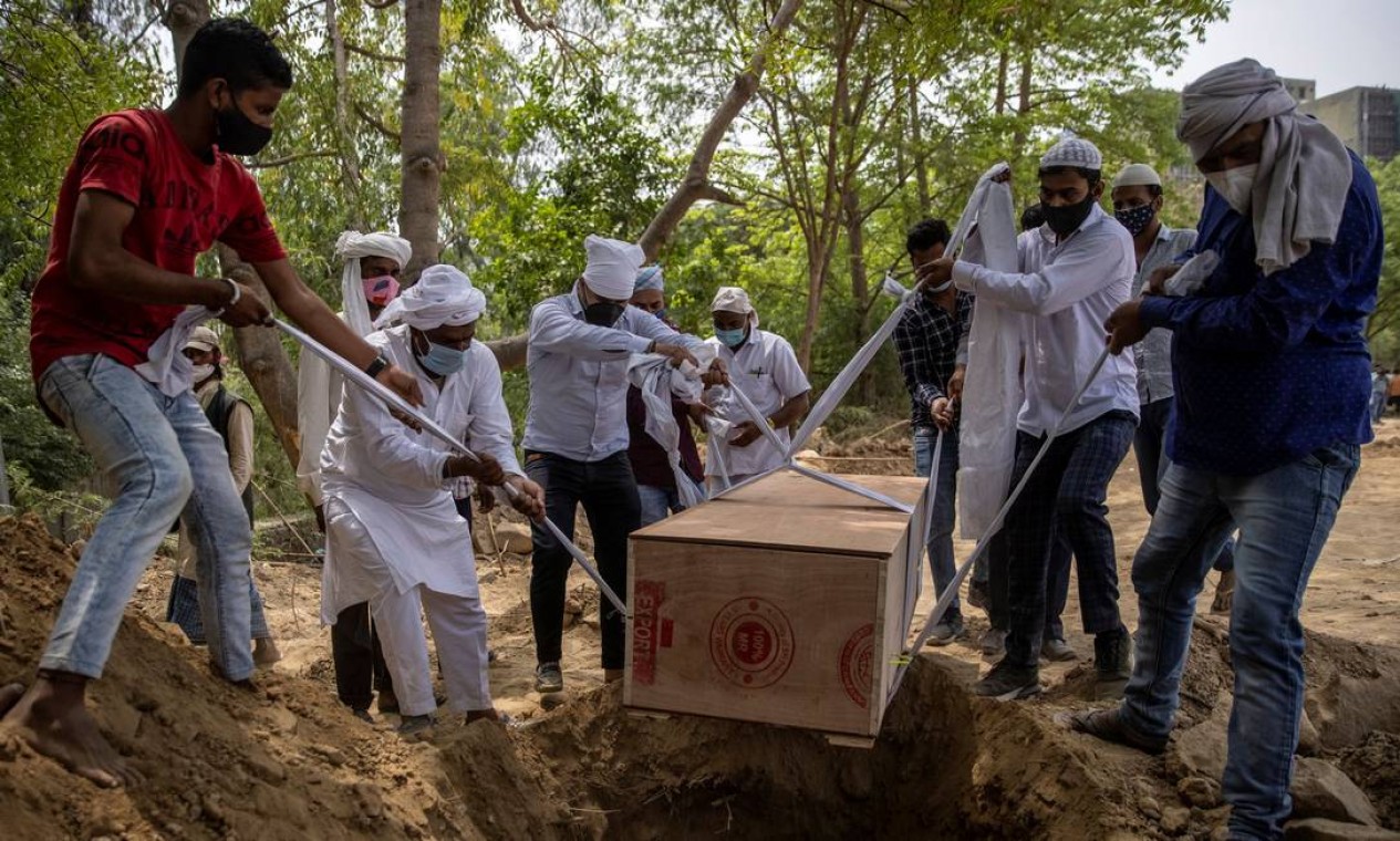Pessoas enterram o corpo de um homem que morreu em decorrência da doença, em um cemitério em Nova Delhi, Índia Foto: DANISH SIDDIQUI / REUTERS - 16/04/2021