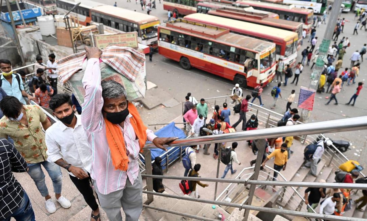As pessoas chegam a uma estação de ônibus em Nova Delhi para retornar a seus lugares nativos, enquanto a Índia enfrenta um pico recorde de infecções por coronavírus Foto: SAJJAD HUSSAIN / AFP