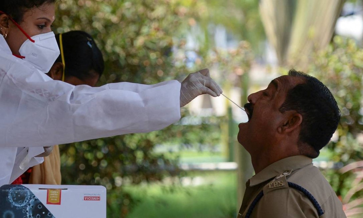 Agente de saúde coleta uma amostra de um policial para um teste de coronavírus RT-PCR, em Chennai Foto: ARUN SANKAR / AFP