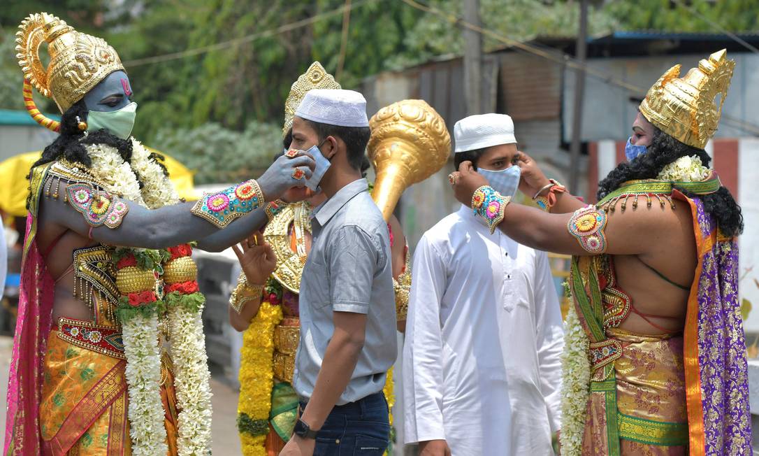 Pessoas vestidas como divindades distribuem máscaras contra a Covid-19 durante campanha de conscientização, na Índia Foto: MANJUNATH KIRAN / AFP
