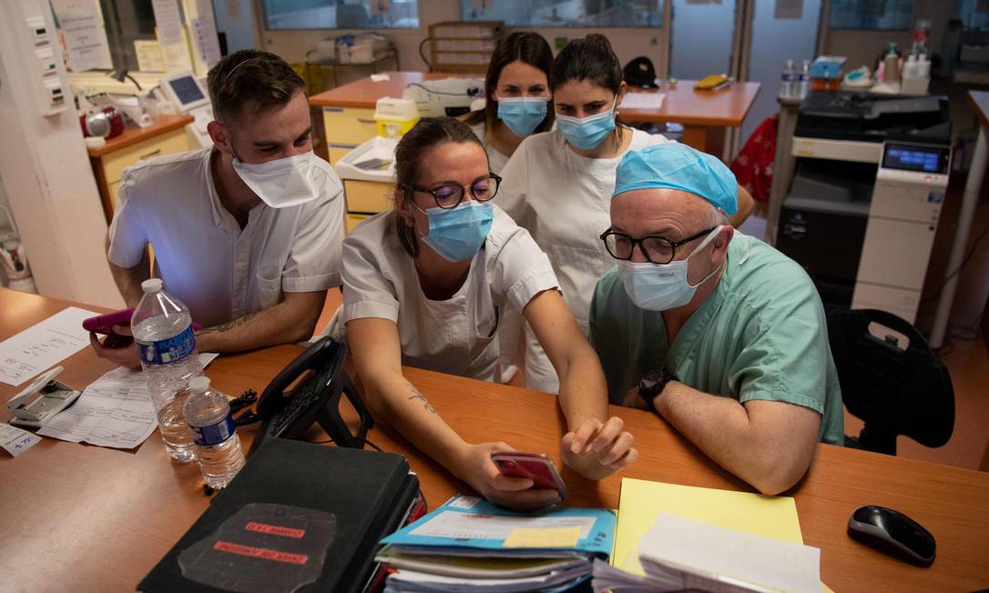 Membros da equipe médica veem informações em um smartphone no hospital UTI Clinique Oceane, na França Foto: LOIC VENANCE / AFP