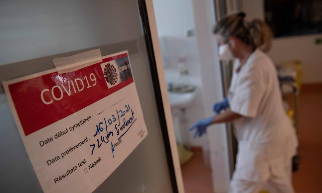 Um membro da equipe calça as luvas antes de cuidar médica de pacientes infectados com Covid-19 na França Foto: LOIC VENANCE / AFP - 20/04/2021