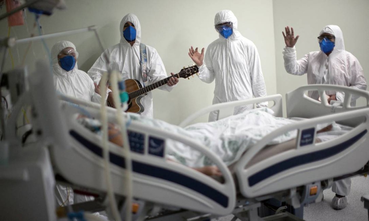 Equipe do hospital de caridade português em Belém, no Pará, canta para um paciente com Covid-19 em um leito do hospital Foto: TARSO SARRAF / AFP - 04/04/2021