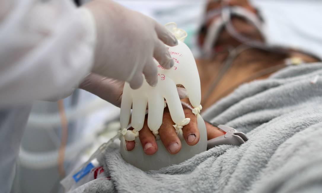 A técnica de enfermagem Semei Araújo Cunha coloca o que chama de &#039;mãozinha do amor&#039;, luvas cheias de água quente, em paciente internado com COVID-19, intubado em Unidade de Pronto Atendimento de São Carlos, São Paulo Foto: AMANDA PEROBELLI / REUTERS - 16/04/2021